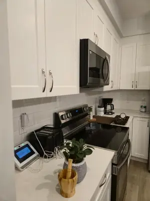 a kitchen with white cabinets and a tablet on a counter at Sunny's Homes in Edmonton