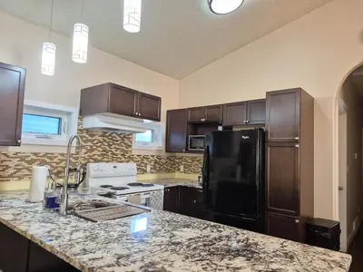 a kitchen with wooden cabinets and a black refrigerator at Central 3 Bedroom Gem Near ICE District - Stadium and Malls in Edmonton