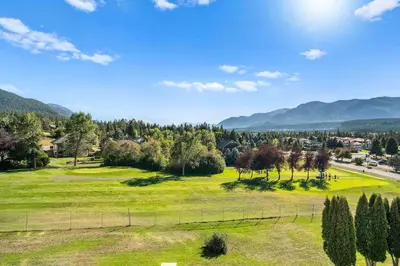 a green field with trees and mountains in the background at The Pinnacle in Fairmont 1BR Condo Near Hot Springs in Fairmont Hot Springs