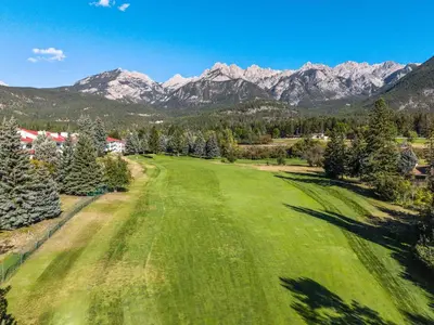 an aerial view of a green field with mountains in the background at The Pinnacle in Fairmont 1BR Condo Near Hot Springs in Fairmont Hot Springs