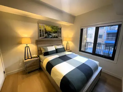 a bedroom with a bed with two lamps and a window at Black Bears Den, Heated Pool, Hot Tub, Brand NEW! in Canmore