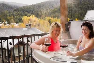 two women in a hot tub with glasses of wine at The Après Arcade in Sun Peaks