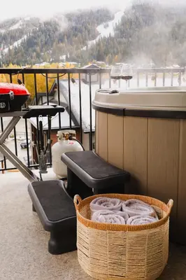 a balcony with a tub and two chairs and a table at The Après Arcade in Sun Peaks