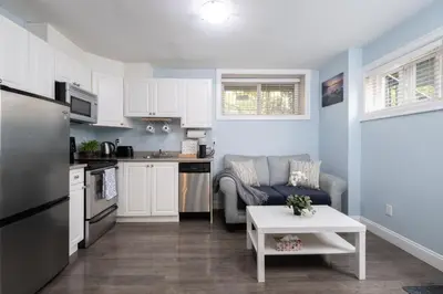 a kitchen and living room with a couch and a table at 2 bedroom suite Walk to SkyTrain, Grocery, Macdonald & more in Vancouver