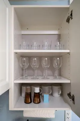 a cupboard filled with wine glasses and other items at 2 bedroom suite Walk to SkyTrain, Grocery, Macdonald & more in Vancouver