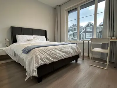 a bedroom with a bed and a chair and a window at Sunny Queen-size Bedroom with Private Bath in Brand New House in Calgary
