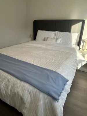 a large white bed with a blue blanket on it at Sunny Queen-size Bedroom with Private Bath in Brand New House in Calgary