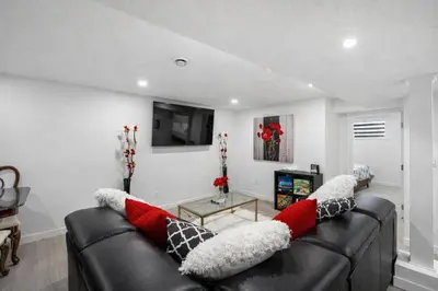 a living room with a black leather couch with red and white pillows at New 2BR Suite, Walk to Dining, Near Downtown in Calgary