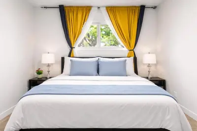 a bedroom with a large bed with yellow curtains at Bright 5-Bed Retreat Near the Zoo and Downtown in Calgary