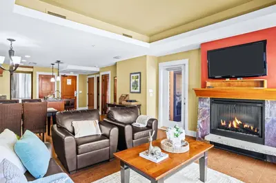 a living room with a fireplace and a tv at Exciting Rockies 1BR Escape with Hot Tub, Pool and BBQ in Canmore