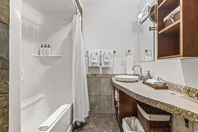 a white bathroom with a tub and a sink at Mountain View 2BR Condo with Hot Tub, Pool and Gym in Canmore