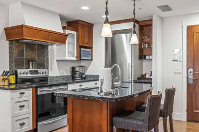 a kitchen with wooden cabinets and a counter top at Mountain View 2BR Condo with Hot Tub, Pool and Gym in Canmore