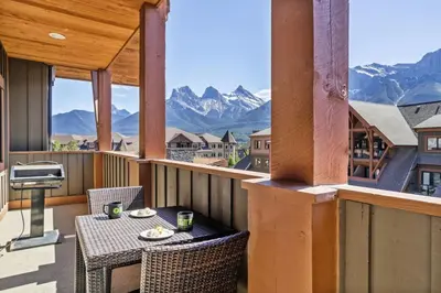 a balcony with a table and chairs and mountains at Spacious Rockies Escape near Banff Hot tub and Gym in Canmore