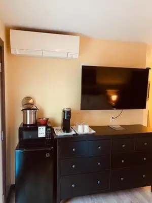 a kitchen with a dresser with a tv and a black refrigerator at Similkameen Valley Resort in Cawston