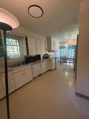 a kitchen with white cabinets and a sink and a table at Vancouver Guest House - Airport 10 Min, Downtown 15 Min - Free Parking & Fast Wi-Fi in Vancouver
