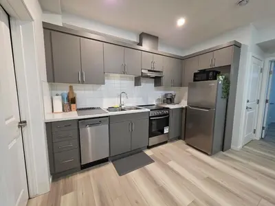 a kitchen with gray cabinets and stainless steel appliances at Amaville - Two BRM Suite in West Edmonton in Edmonton