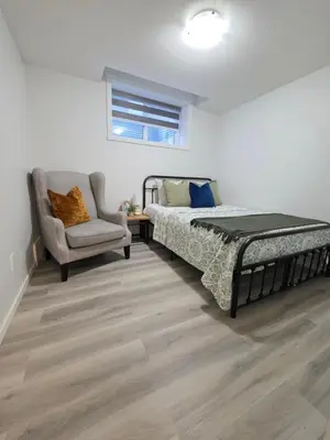 a bedroom with a bed and a chair at Amaville - Two BRM Suite in West Edmonton in Edmonton
