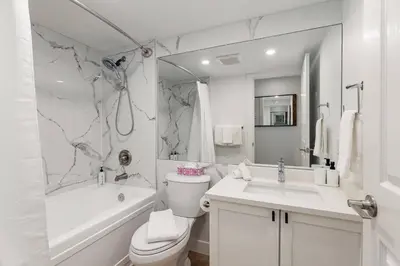 a white bathroom with a toilet and a tub and a sink at Private Hot Tub | Pool | Free Parking | Sauna in Whistler