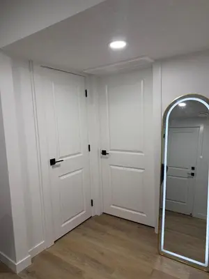 a hallway with white doors and a mirror at Cozy 2 Bedroom Suite Close to Amenities in Edmonton