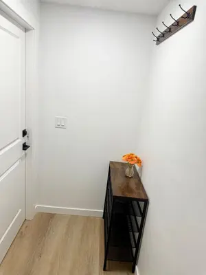 a hallway with a table and a white wall at Cozy 2 Bedroom Suite Close to Amenities in Edmonton