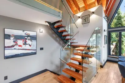 a glass staircase in a house with a blue couch at Luxury Whistler 6BR Chalet, Hot Tub and Music Loft in Whistler