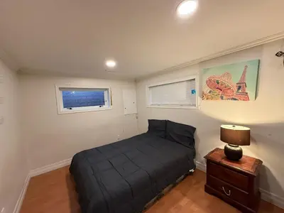 a small bedroom with a bed and a night stand at Downtown Central City Cozy Private 2 Bedroom Basement Suite - Independent Entry in Surrey