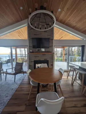 a living room with a table and a fireplace at Serenity on the Vista's Point at Lac La Nonne in Onoway