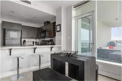a kitchen with a table and a large window at The Spruce Modern 2BR Condo with Pool & Parking in Calgary