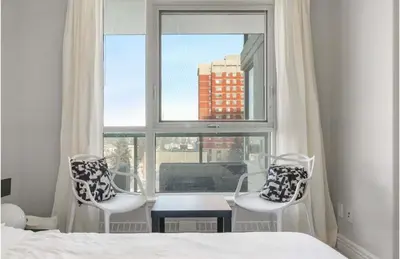 a bedroom with a bed and two chairs and a window at The Spruce Modern 2BR Condo with Pool & Parking in Calgary