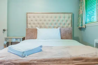 a bed with a large headboard with two towels on it at South Vancouver Garden Home in Vancouver