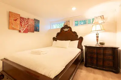 a bedroom with a bed and a dresser with a lamp at South Vancouver Garden Home in Vancouver