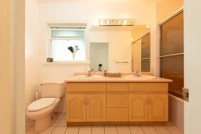 a bathroom with a toilet and two sinks and a mirror at South Vancouver Garden Home in Vancouver