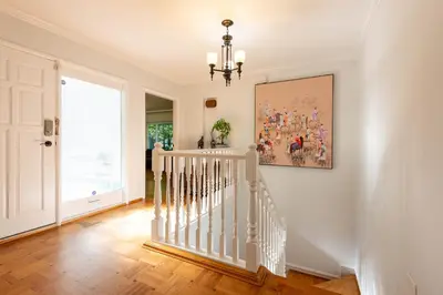 a white staircase in a home with a painting on the wall at South Vancouver Garden Home in Vancouver