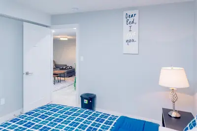 a bedroom with a blue bed and a table at Superior and Spacious 2-bedroom basement private suite in Edmonton