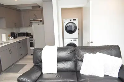 a black leather couch in a kitchen with a washing machine at Beautiful Basement Suite in Stillwater, West Edmonton in Edmonton