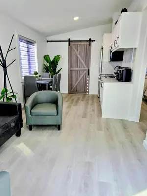 a living room with a green chair and a kitchen at The Oasis in Stettler in Stettler