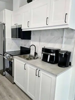 a kitchen with white cabinets and a sink and refrigerator at The Oasis in Stettler in Stettler