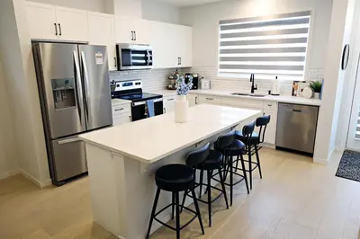 a kitchen with a large white island with bar stools at Seton 4BR Family Home 5 Min to South Campus in Calgary
