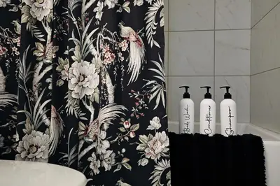 a bathroom with a black and white floral shower curtain at Seton 4BR Family Home 5 Min to South Campus in Calgary