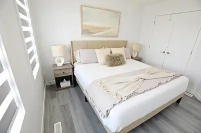 a bedroom with a large bed with white sheets at Chappelle with AC King Beds Fenced Yard Garage in Edmonton