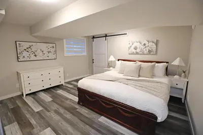 a bedroom with a large bed and wooden floors at Mahogany Lakefront 2BR Walkout Trails And Privacy in Calgary