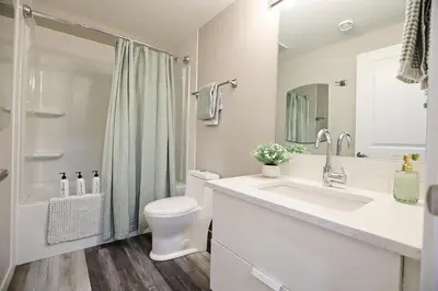 a white bathroom with a toilet and a sink at Mahogany Lakefront 2BR Walkout Trails And Privacy in Calgary
