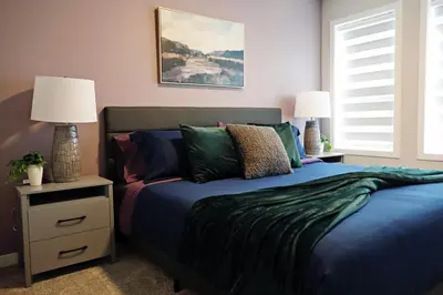 a bedroom with a blue bed and two lamps at Edgemont Getaway King Bed Garage WEM And DisneyPlus in Edmonton