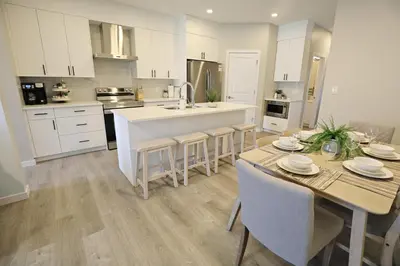 a kitchen with white cabinets and a table and chairs at Edgemont Getaway King Bed Garage WEM And DisneyPlus in Edmonton