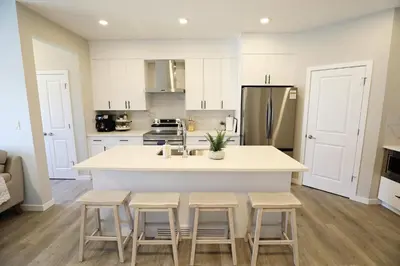 a kitchen with white cabinets and a kitchen island with stools at Edgemont Getaway King Bed Garage WEM And DisneyPlus in Edmonton
