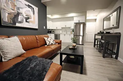 a living room with a brown couch and a kitchen at Edgemont Getaway King Bed Garage WEM And DisneyPlus in Edmonton