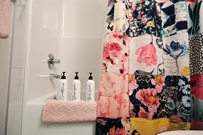 a shower curtain in a bathroom with bottles on a counter at Edgemont Getaway King Bed Garage WEM And DisneyPlus in Edmonton
