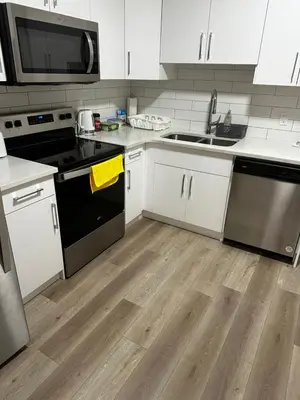 a kitchen with black and white appliances and wooden floors at Bedroom in the basement Upland 1 in Edmonton