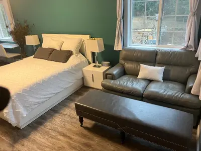 a bedroom with a bed and a leather couch at Ellison Funny Farm in Barrière