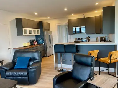 a kitchen with black leather chairs and a kitchen counter at The Golden Sky Sanctuary at the Algonquin Residence in Prince Rupert